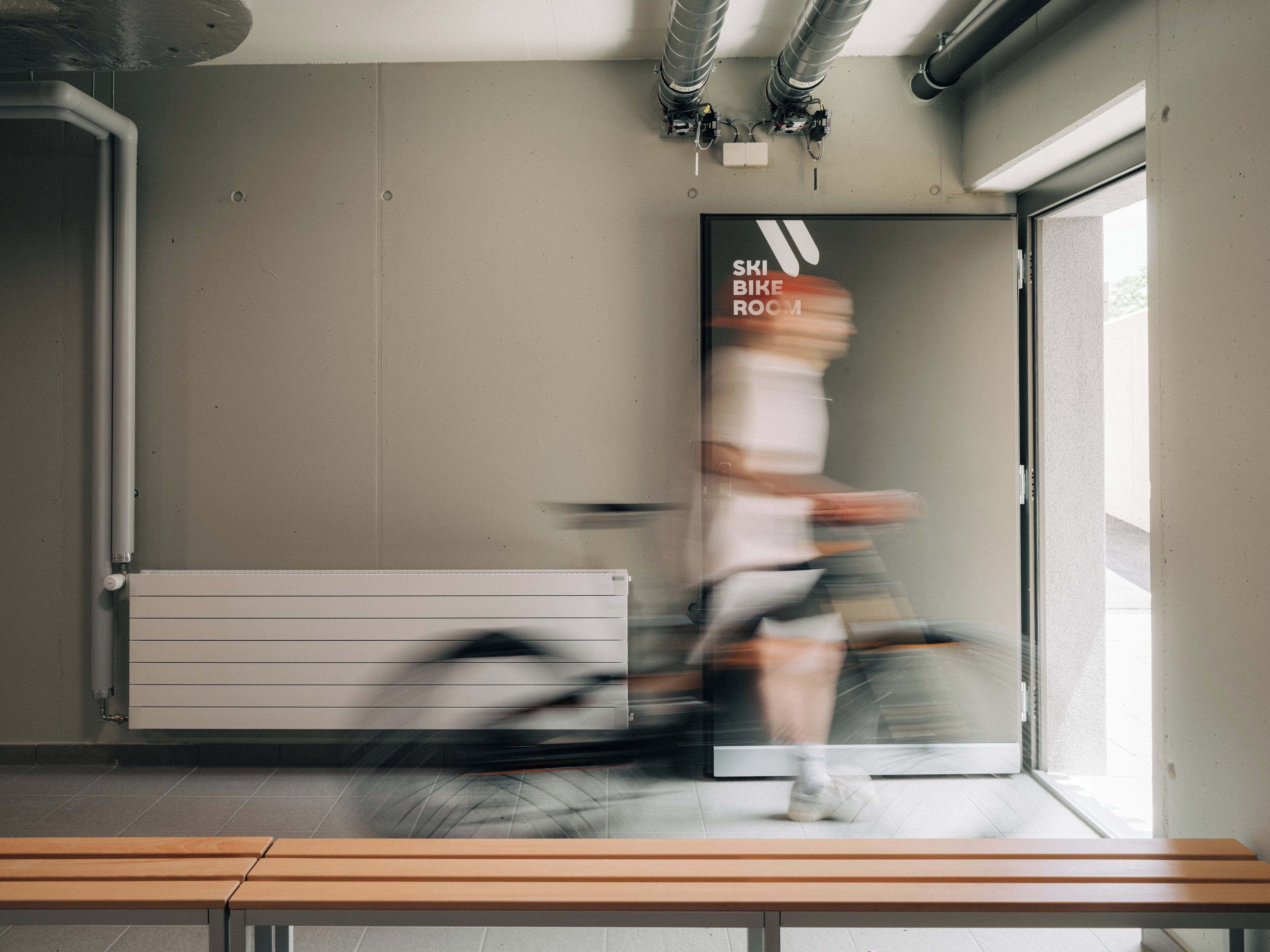 A room with a bench, a radiator, and a sign reading "SKI BIKE ROOM".