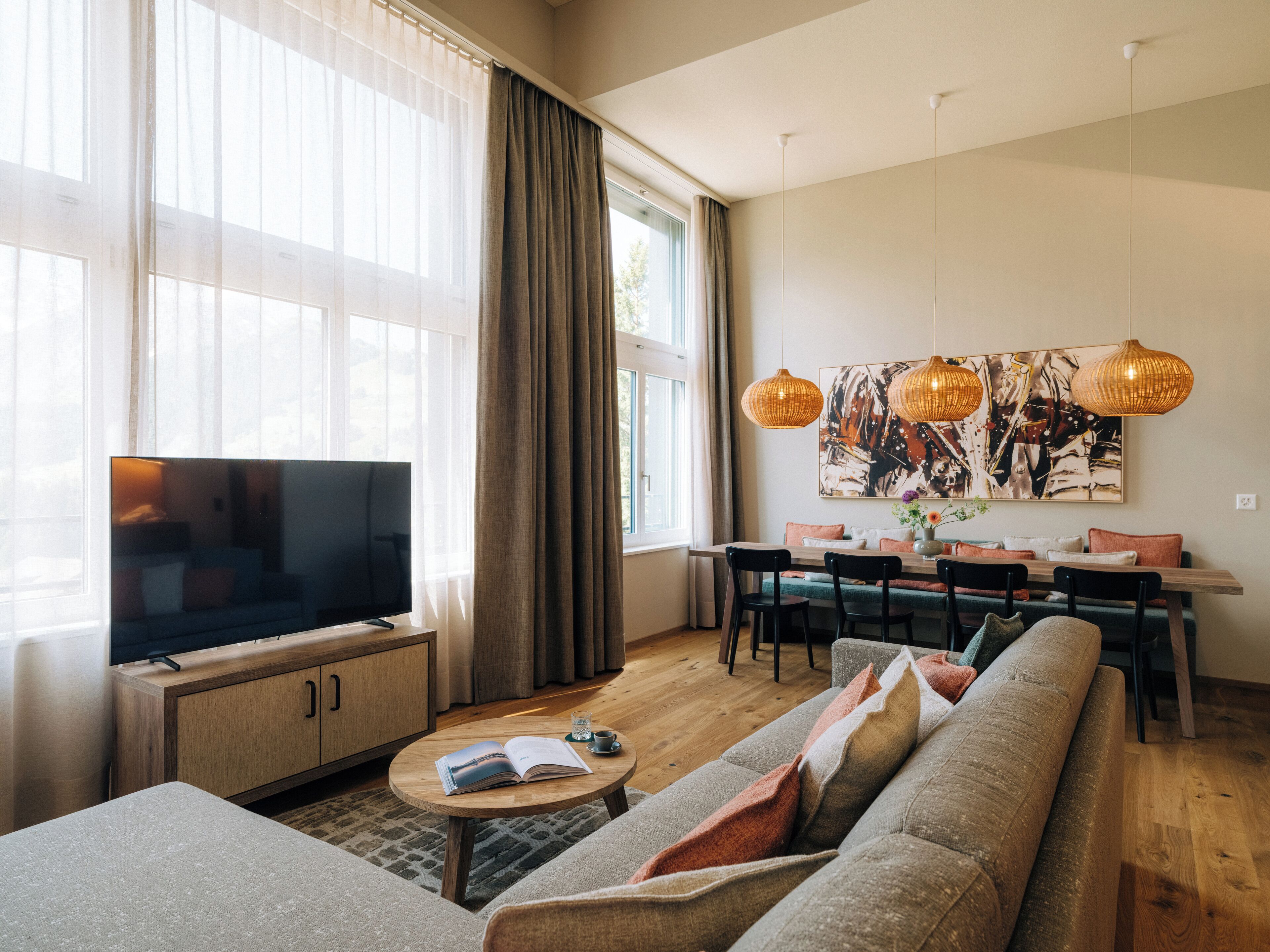 Een moderne woonkamer met een grote televisie, houten meubels en een eethoek met een tafel en stoelen.