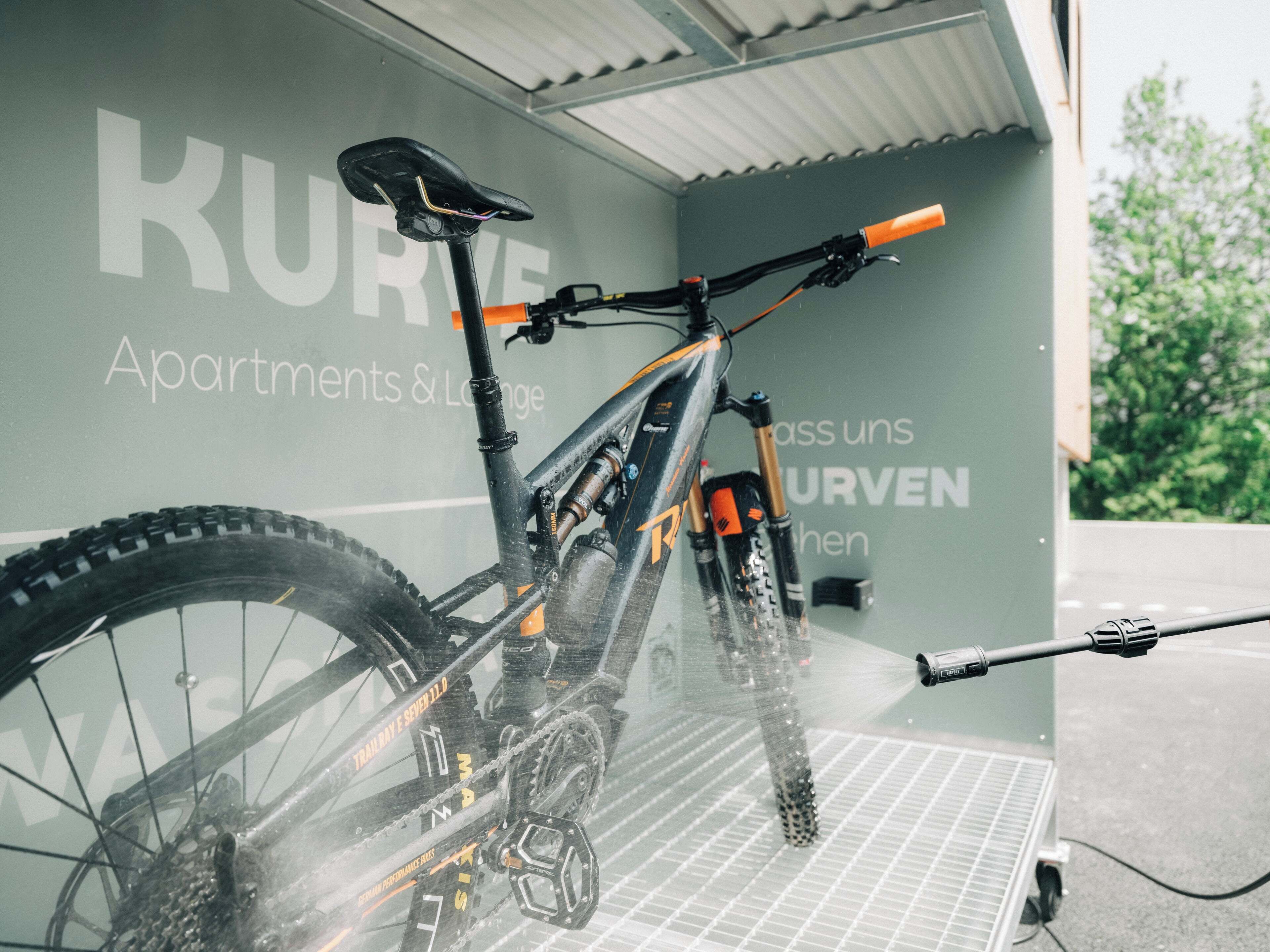 A bicycle in a room with a sign reading "KURVE Apartments & Lounge".