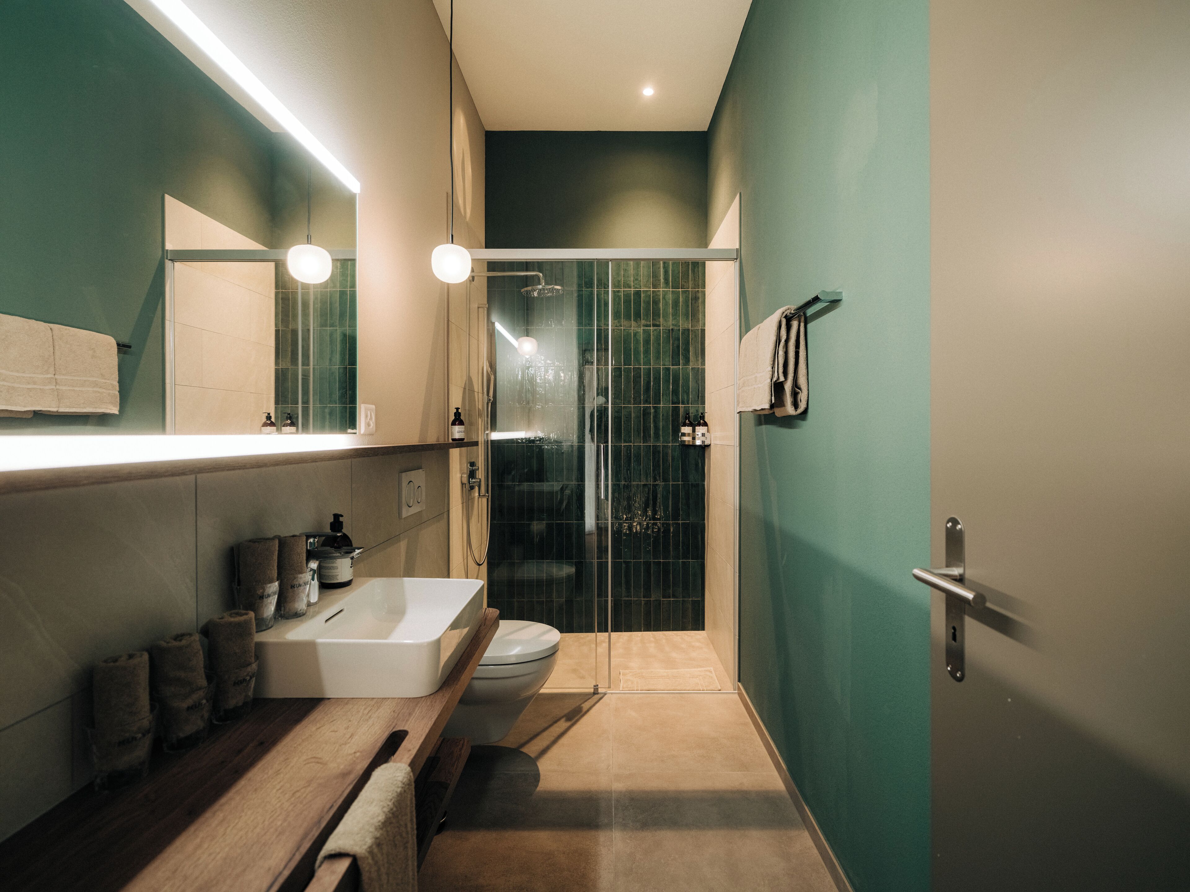 A modern bathroom with a white sink, mirror, and toilet.