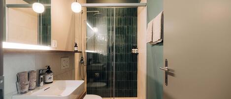 Une salle de bain moderne avec une douche Ă lâitalienne en verre, un lavabo blanc et des toilettes.