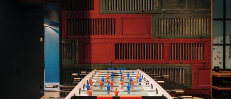 A foosball table in a room with a red and green wall paneling and a blue door.