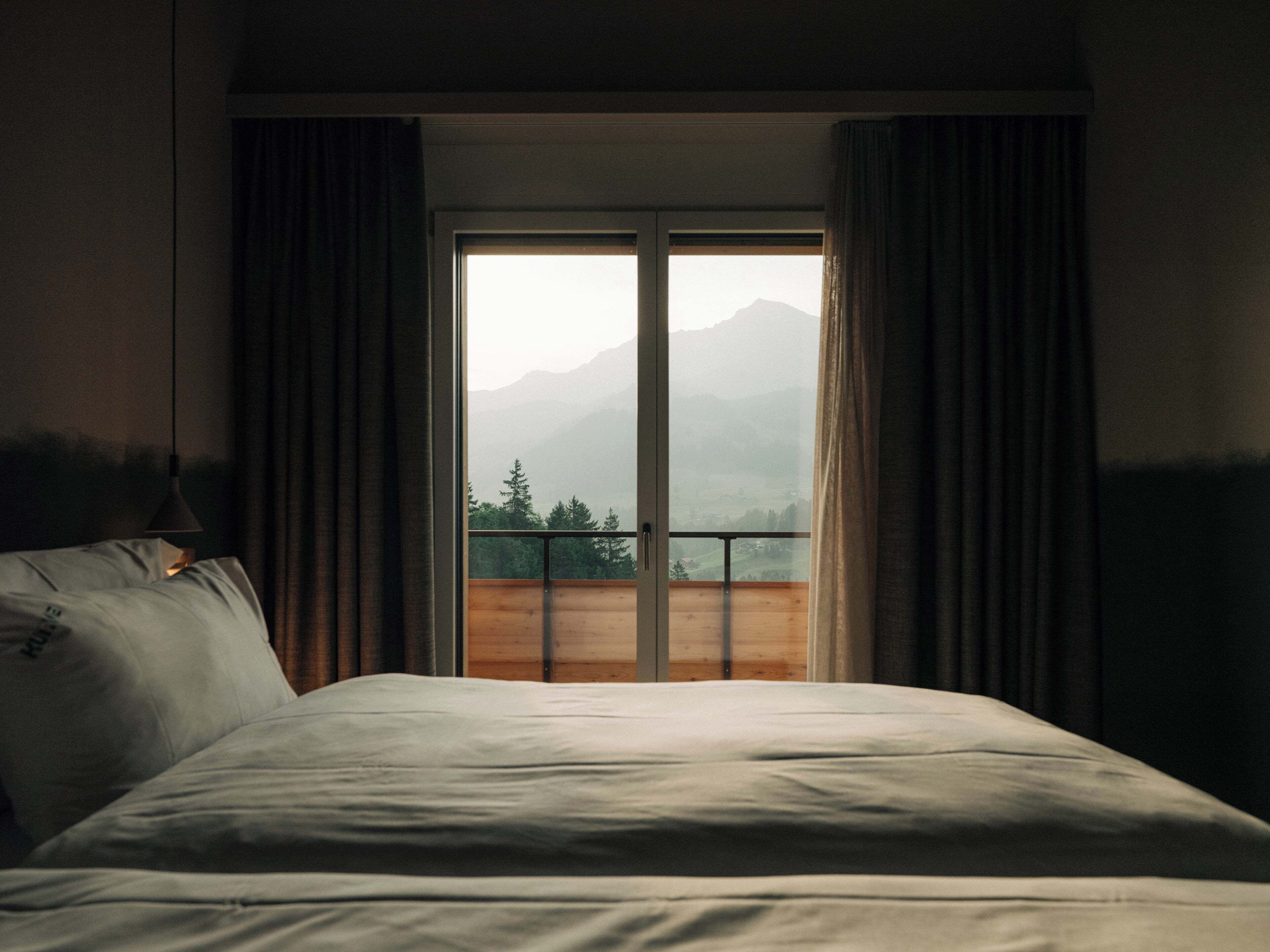 A bedroom with a bed, a window, and curtains.