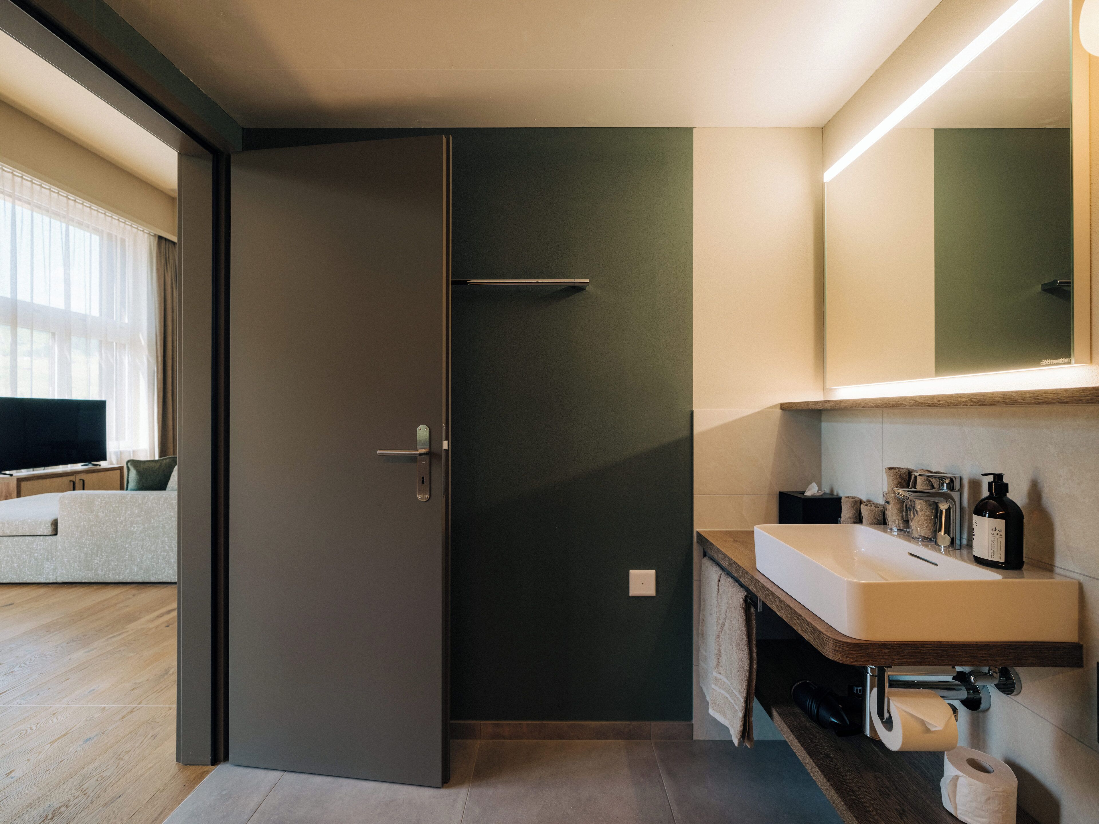 A modern bathroom with a dark door, a sink, and a mirror.