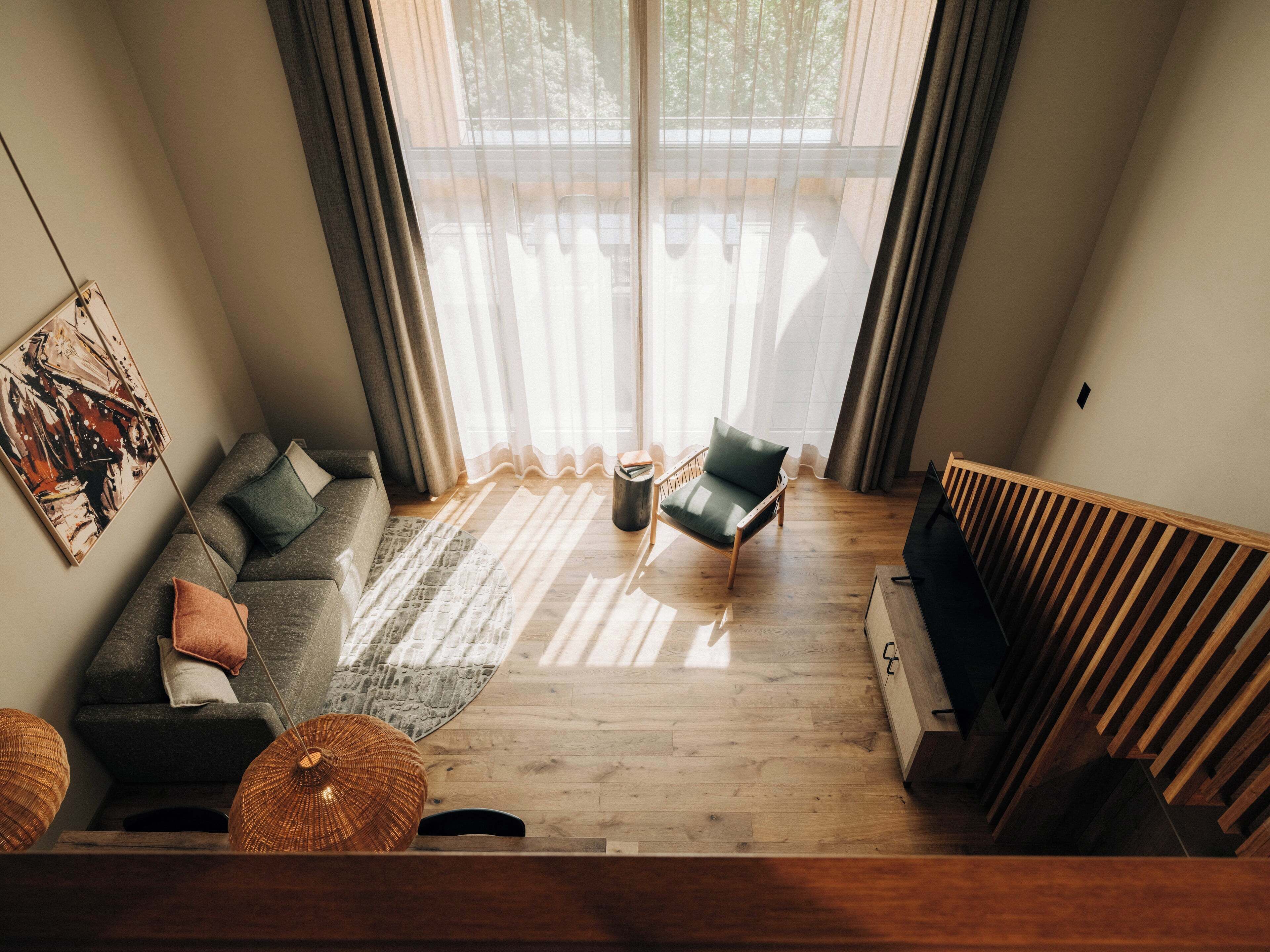 A modern living room with a sectional sofa, a single chair, a coffee table, and a large window with sheer curtains.