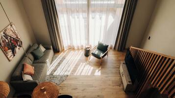 A modern living room with a sectional sofa, a single chair, a coffee table, and a large window with sheer curtains.