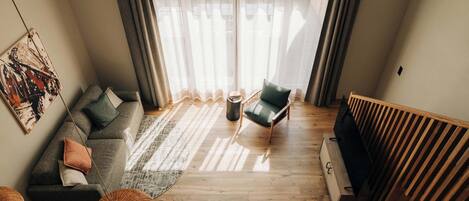 A modern living room with a sectional sofa, a single chair, a coffee table, and a large window with sheer curtains.