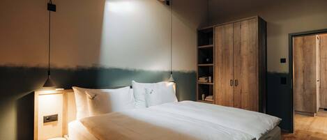 Un dormitorio con cama, armario de madera y mesita de noche.