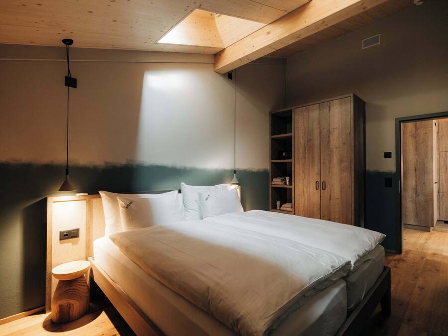 A bedroom with a bed, wooden wardrobe, and a nightstand.