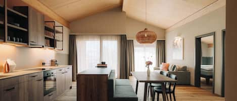 A modern kitchen with wooden cabinets, a dining area with a table and chairs, and a cozy seating area with a sofa and cushions.