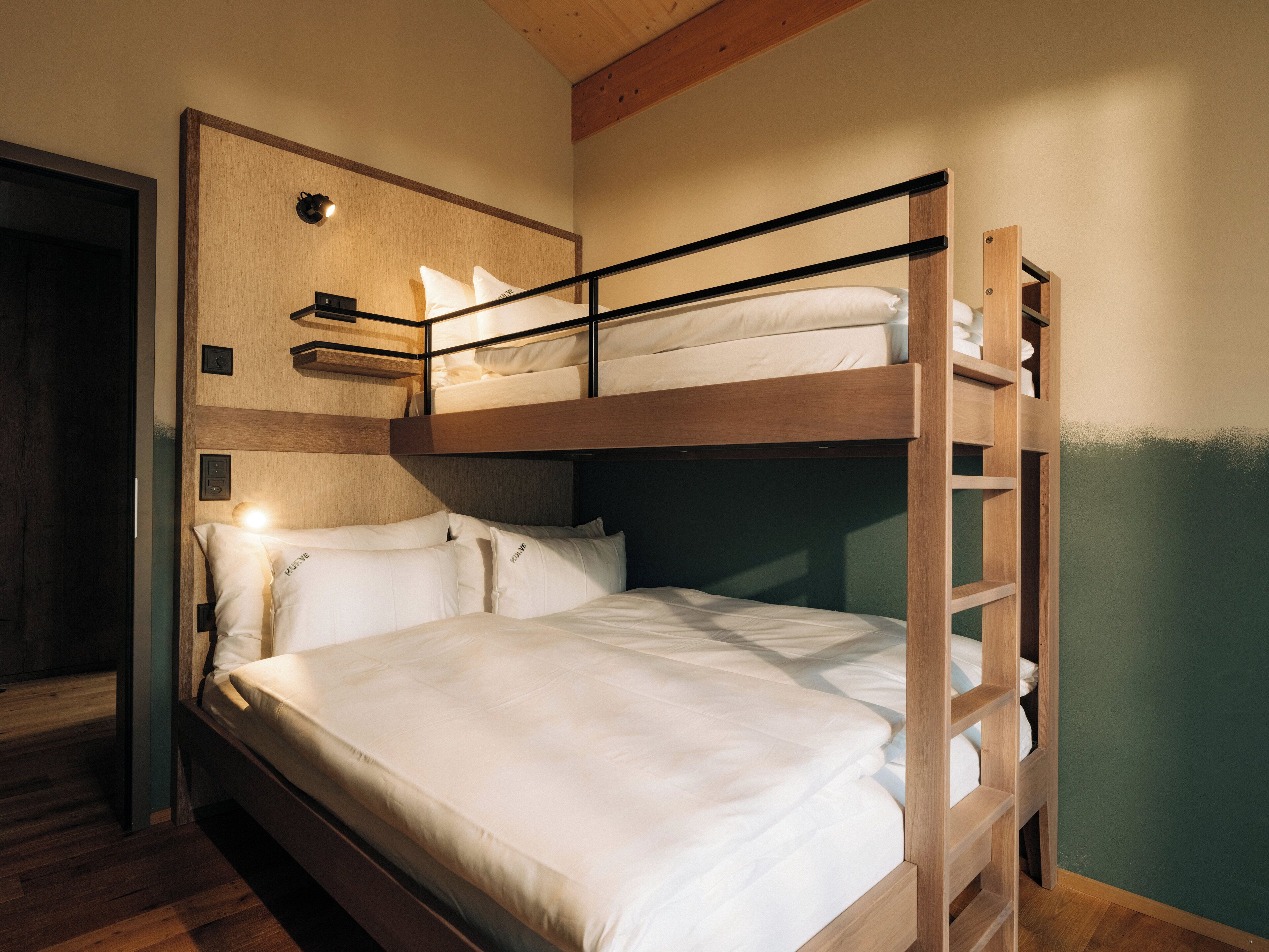 A bunk bed room with a wooden headboard, a small shelf, and a wall-mounted light.