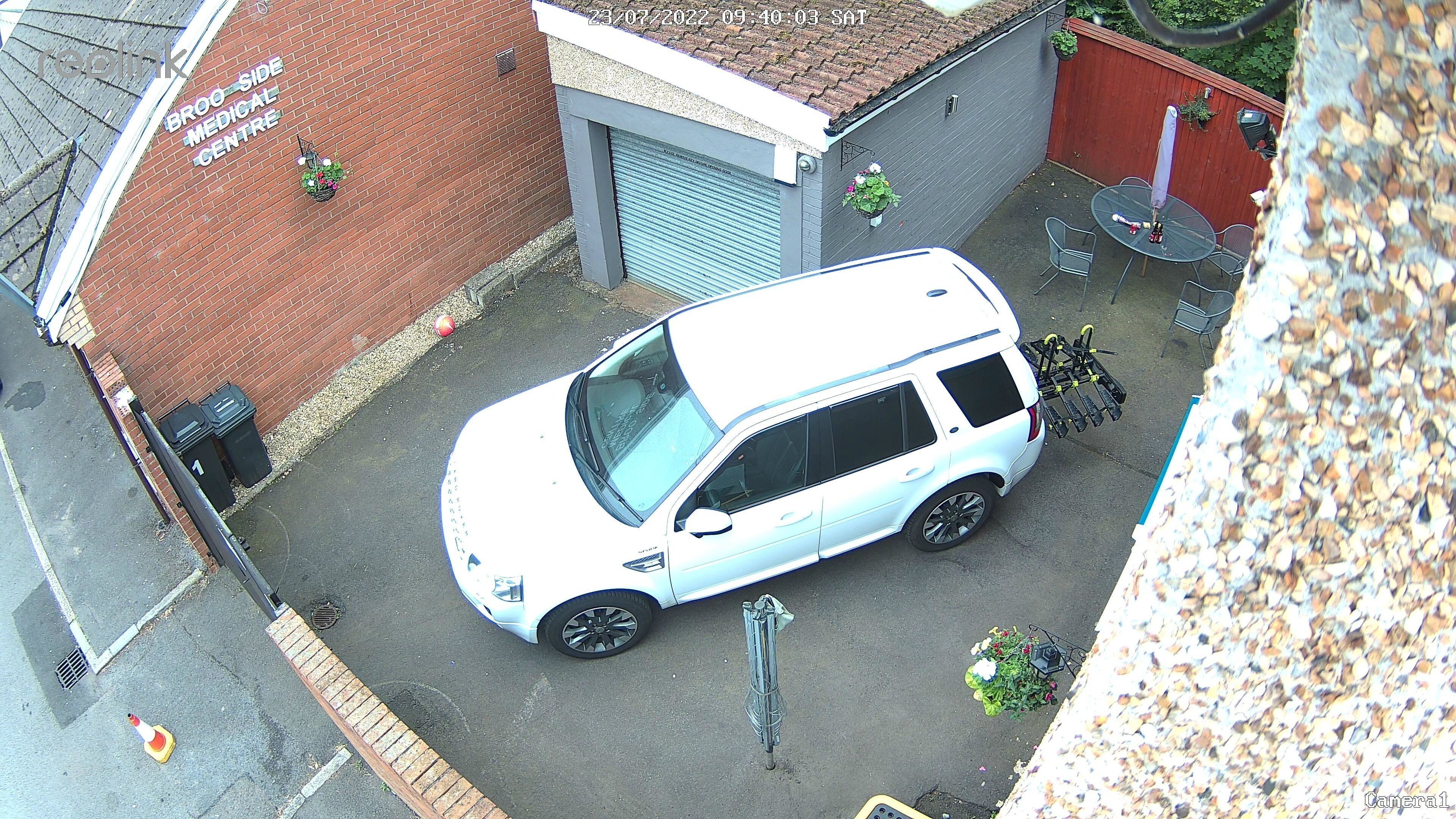Un SUV blanco estacionado en una entrada de casa con un garaje y un centro médico al fondo.