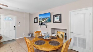 A dining room with a round table, six chairs, a painting, and a fireplace. - Marlin by South Padre Resort Rentals (South Padre Island)