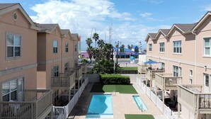 A residential building with multiple balconies, a swimming pool, and a clear view of the ocean. - Marlin by South Padre Resort Rentals (South Padre Island)