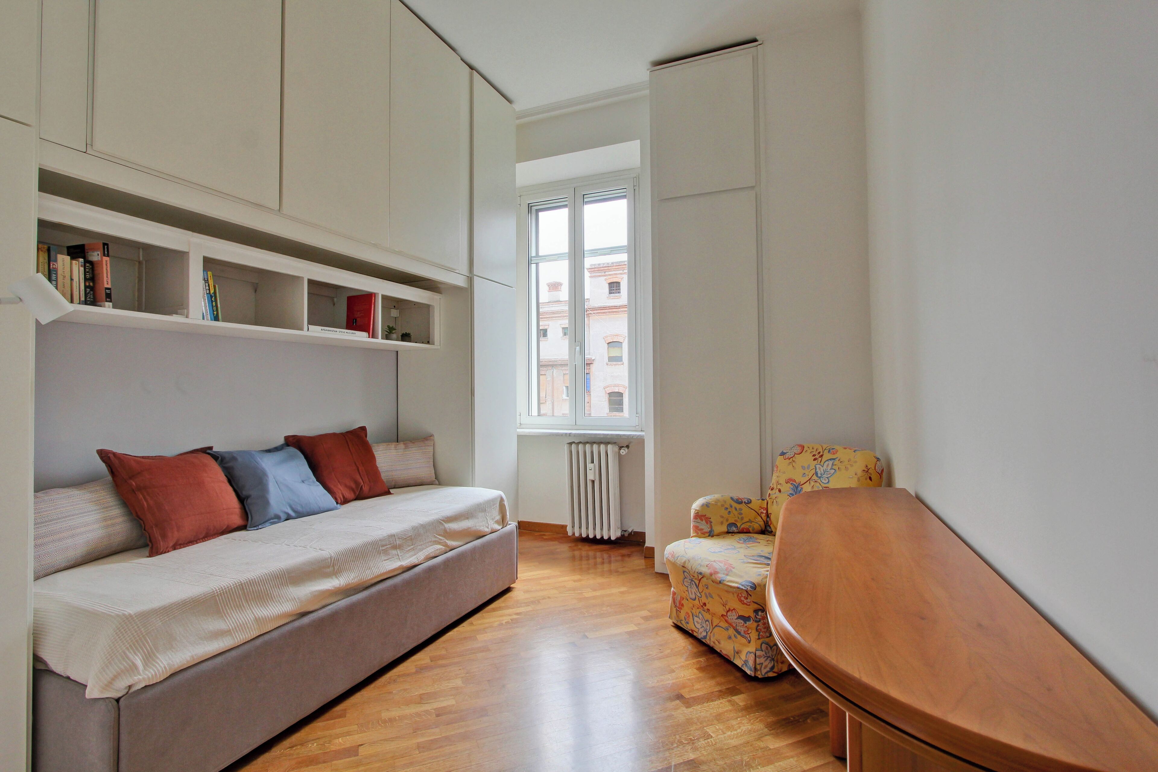 A compact room with a sofa, a small chair, and built-in shelving.