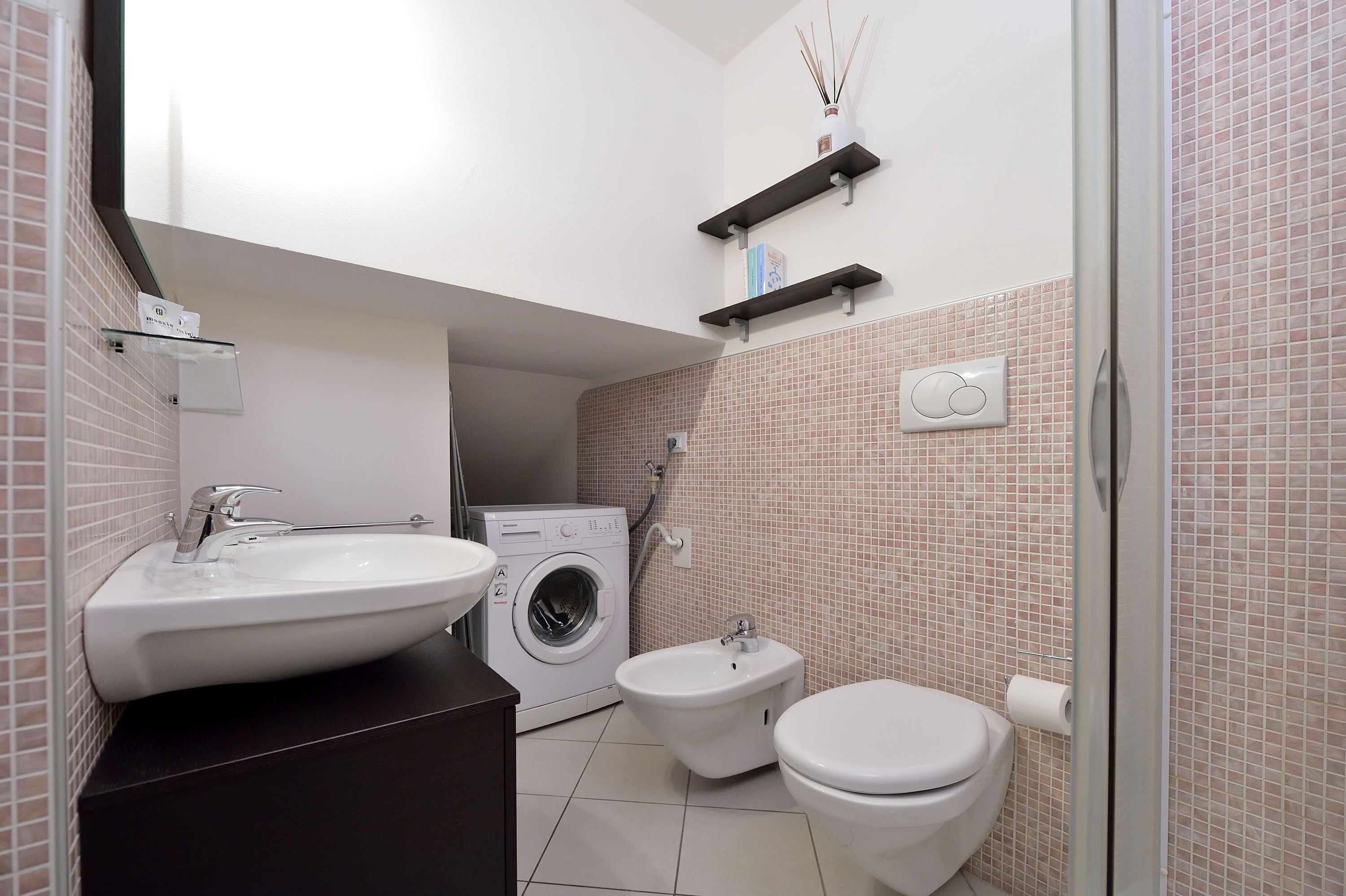 A modern bathroom with a sink, bidet, toilet, and washing machine.