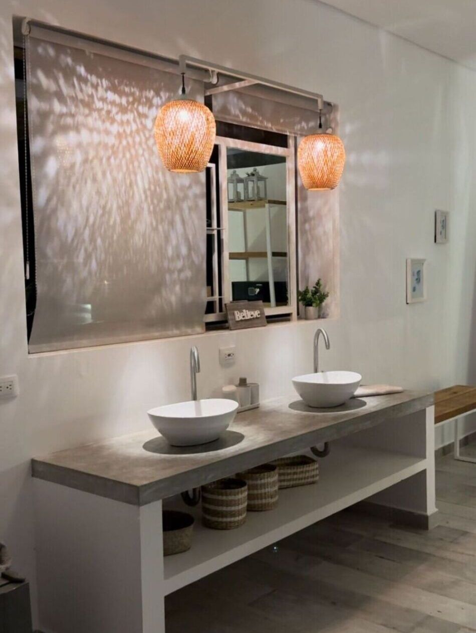 A modern bathroom with a large mirror, two sinks, and pendant lights.