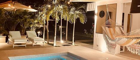 A swimming pool with lounge chairs and palm trees.