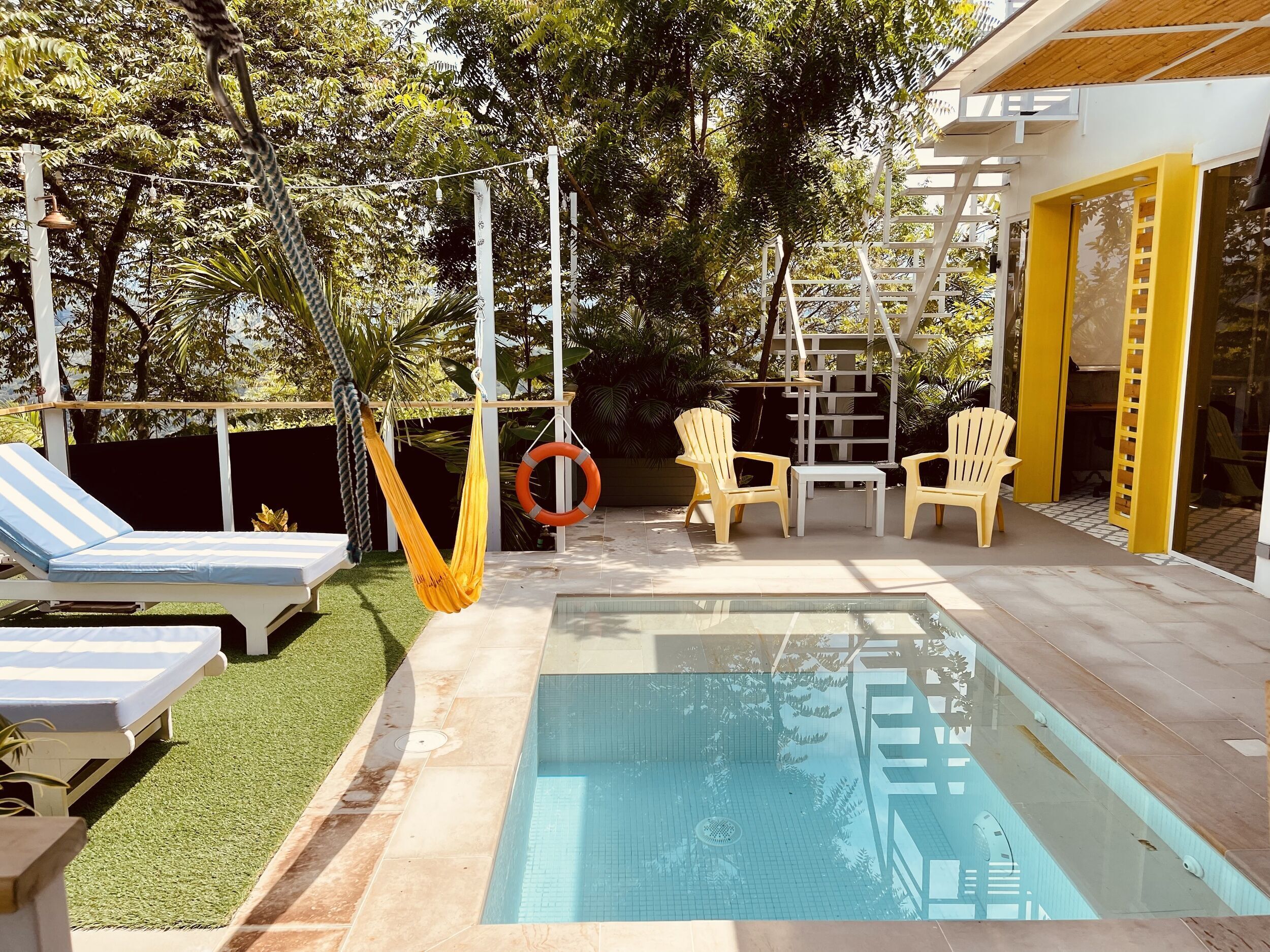 A pool area with a hammock, lounge chairs, and a lifebuoy.