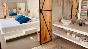 A modern bedroom with a bed, bedside tables, a large mirror, and a bathroom with a sink and toilet. - CasaDorothea (Apulo)