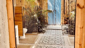 A covered outdoor area with a patterned floor, wooden beams, and a blue gate. - CasaDorothea (Apulo)