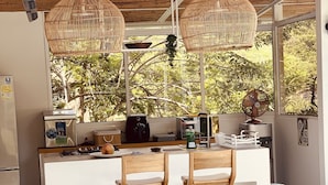 A modern kitchen with a large island, two wooden chairs, and a view of a swimming pool. - CasaDorothea (Apulo)