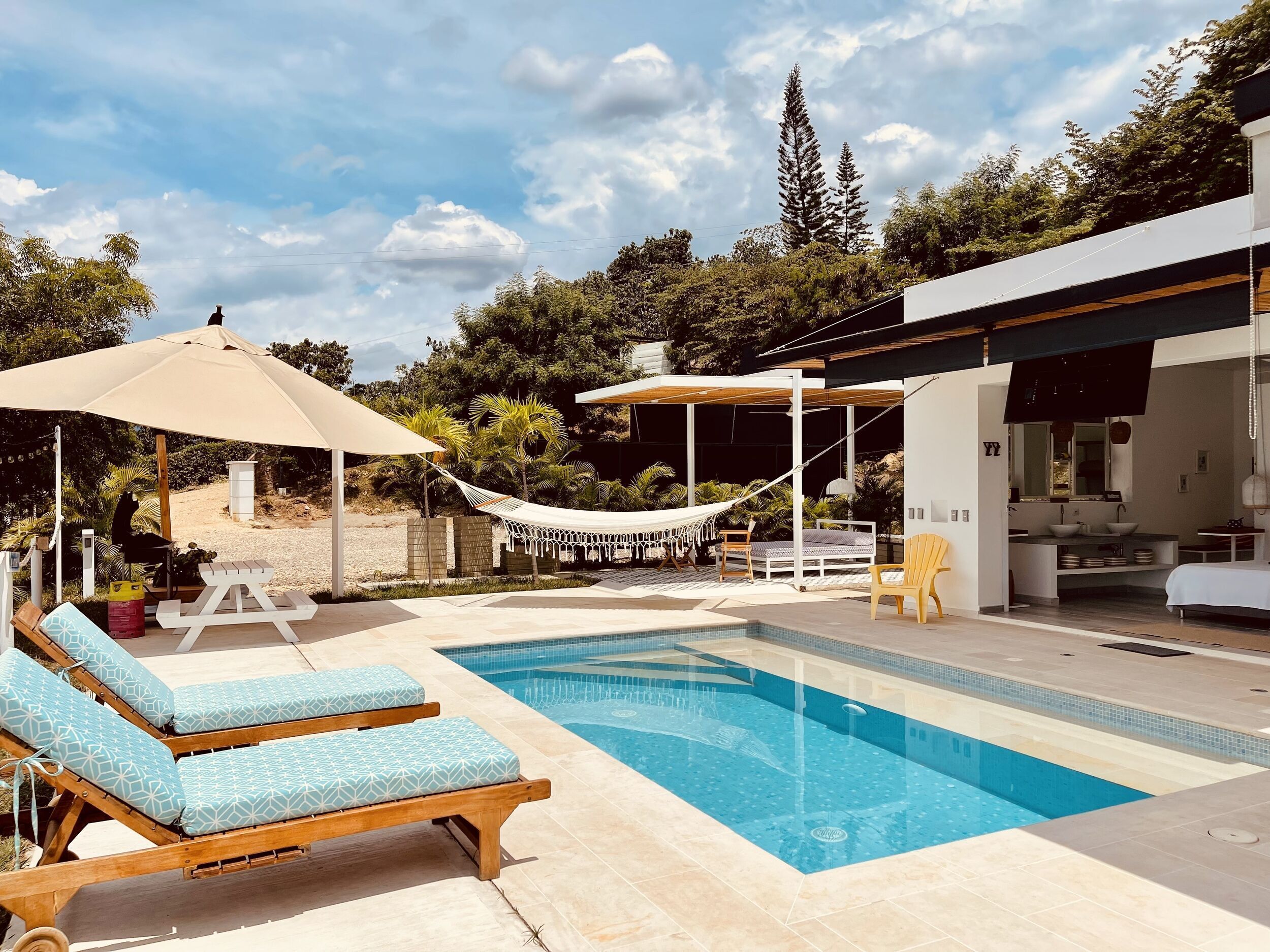 A pool area with lounge chairs, a hammock, and a covered seating area.