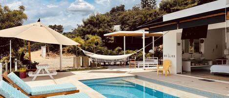 A pool area with lounge chairs, a hammock, and a covered seating area.