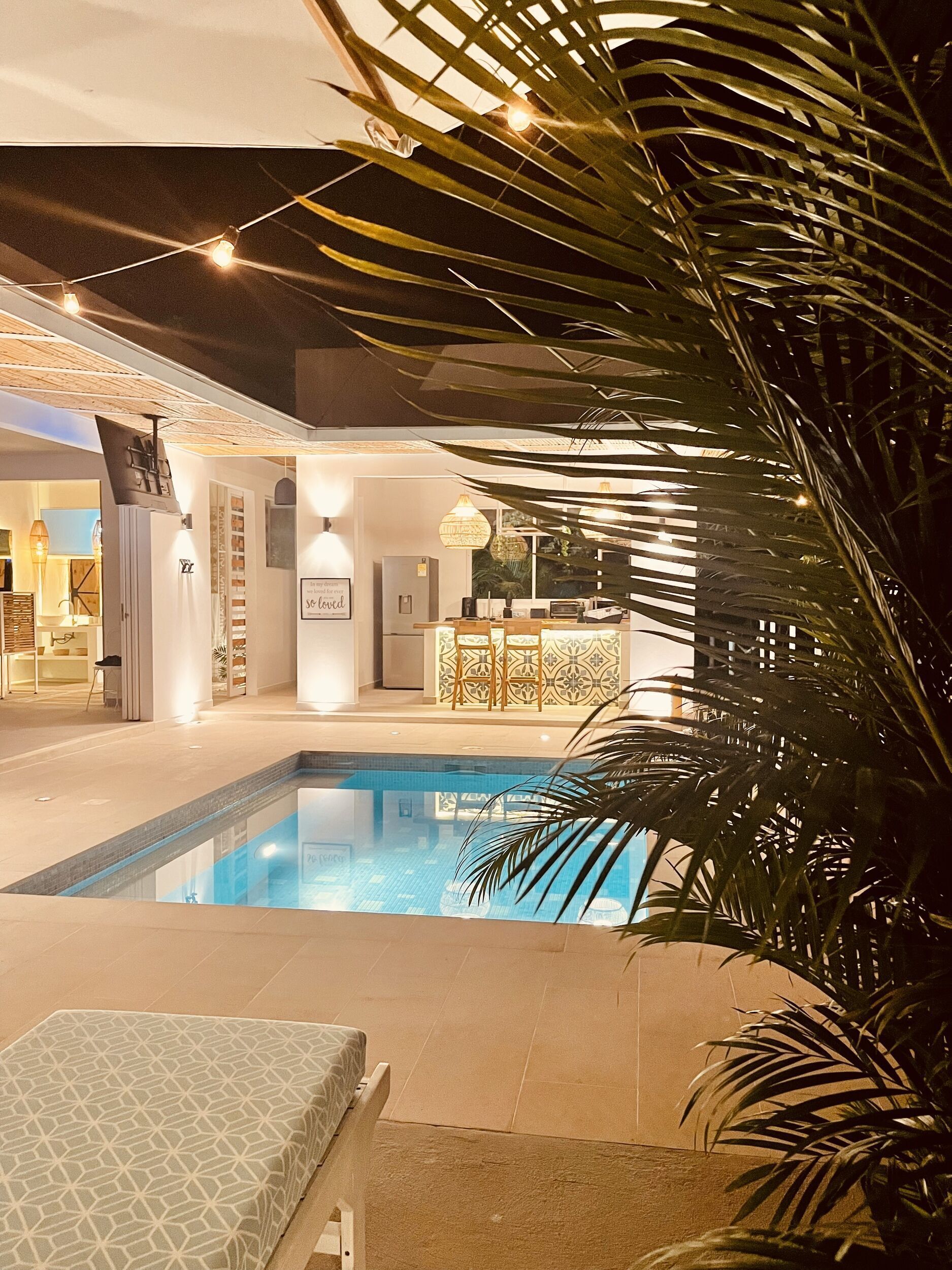 A pool area with a lounge chair, a bar area, and a dining space.
