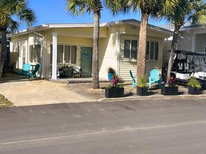 Une maison de plain-pied avec un porche, un espace salon extérieur et un véhicule garé.