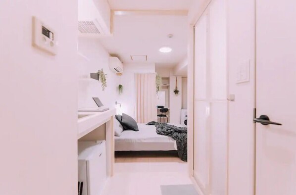 A narrow hallway with a bed, a desk, and a wardrobe. - Minimalist Loft 402 (Osaka)