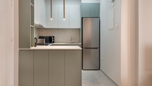 Una cocina moderna con microondas integrado, refrigerador de acero inoxidable y luces colgantes.