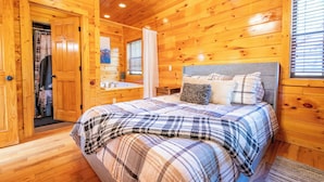 A wooden cabin bedroom with a bed, a nightstand, and a window with blinds. - *Creekside 1BD + Loft Cabin! Hot Tub + Fire Pit!* (Sevierville)