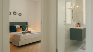 A bedroom with a bed, bedside table, lamp, and wall decorations. - Rafael Green Home (Como)