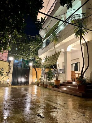 A courtyard with a gated entrance, potted plants, and a staircase leading to an upper level. - Mandarine Hostel (Tirana)