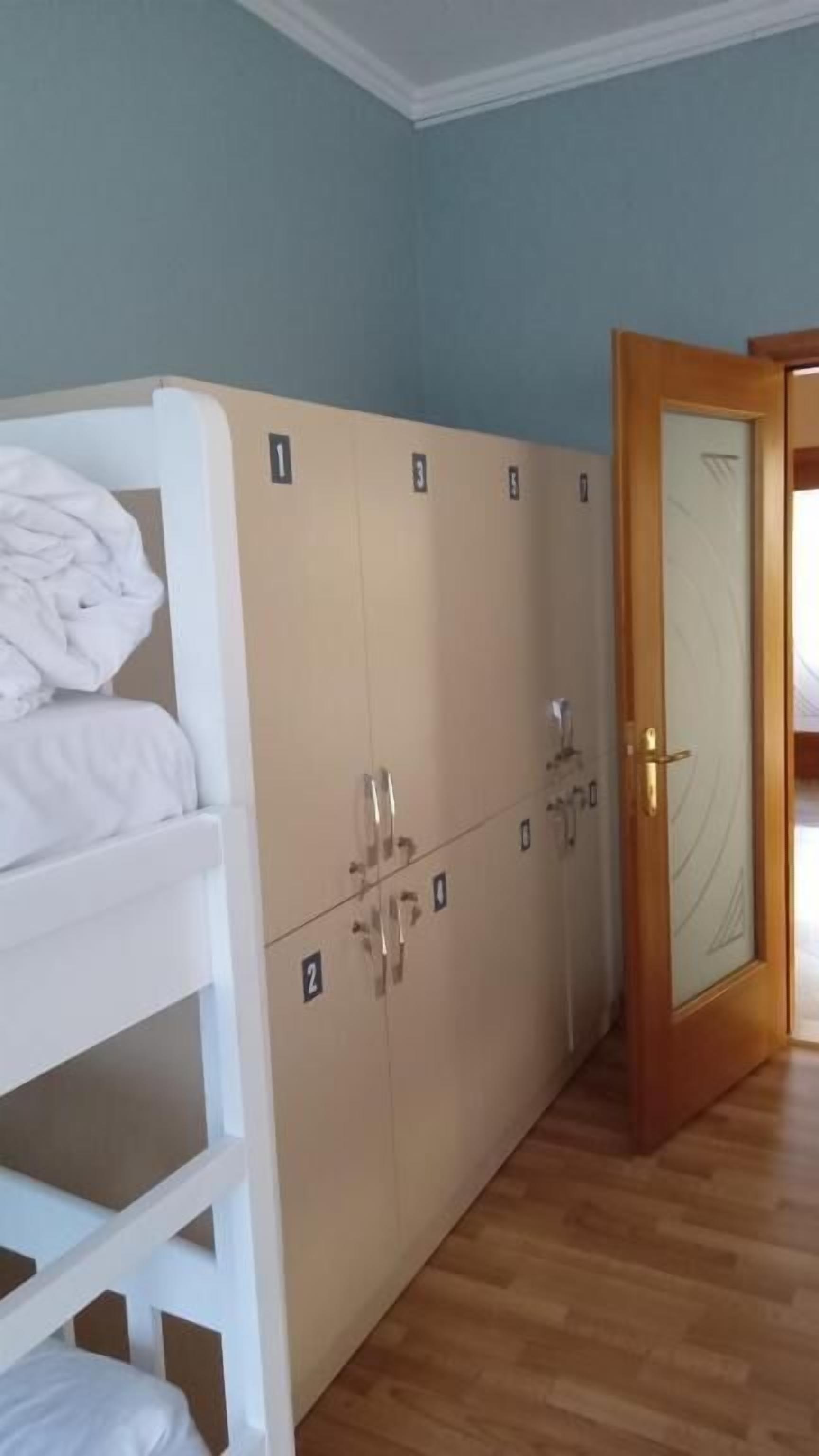 A room with bunk beds, a wooden floor, and a door with a mirror.