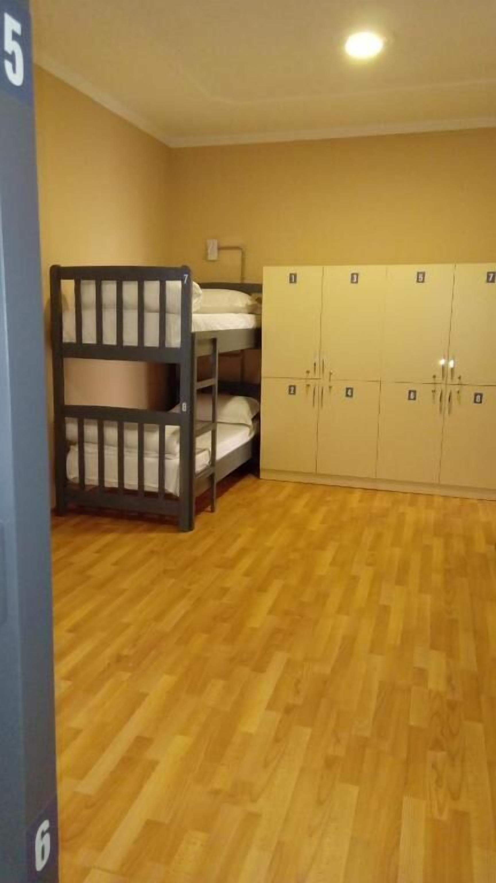 A room with a bunk bed, a wardrobe with multiple doors, and a wooden floor.