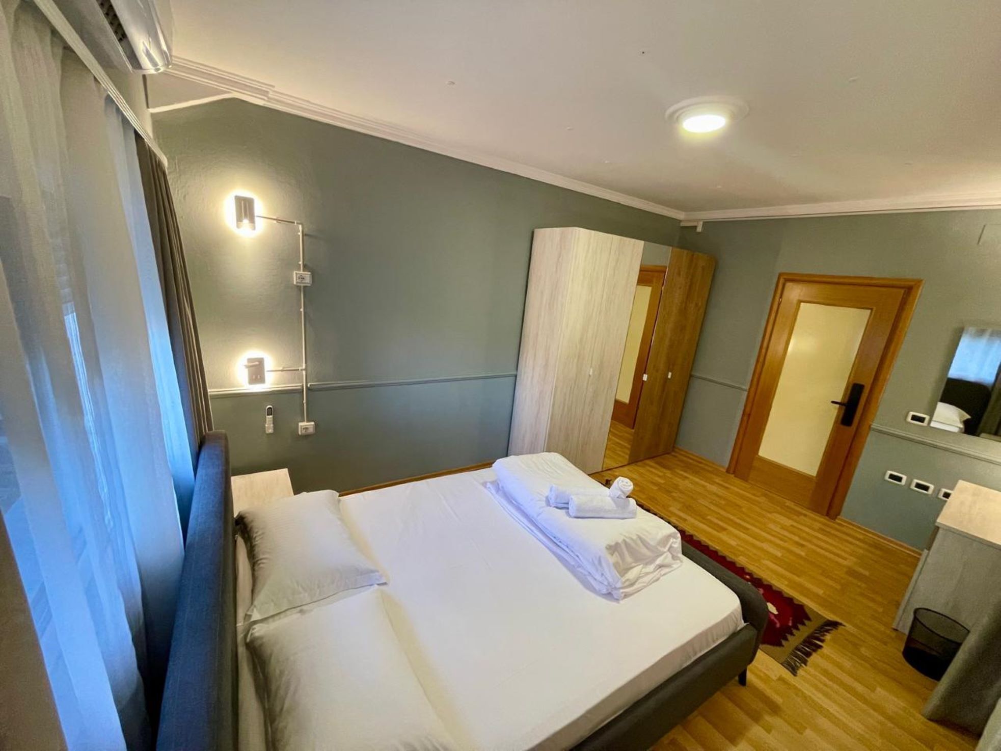 Una habitación de hotel con cama, mesita de noche y espejo.