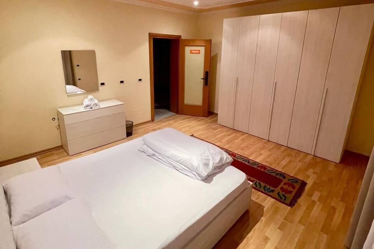 A bedroom with a bed, a dresser, a mirror, and a wardrobe.