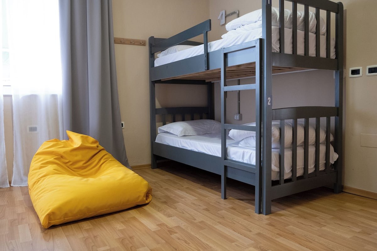 A bunk bed room with a yellow bean bag chair and a wooden floor.