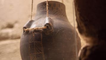 A hanging pottery piece with geometric patterns, suspended by strings.