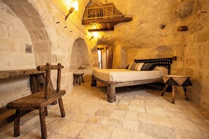 A rustic stone room with a bed, wooden bench, and a small table. - Moyseion Matera - Adults Only (Matera)