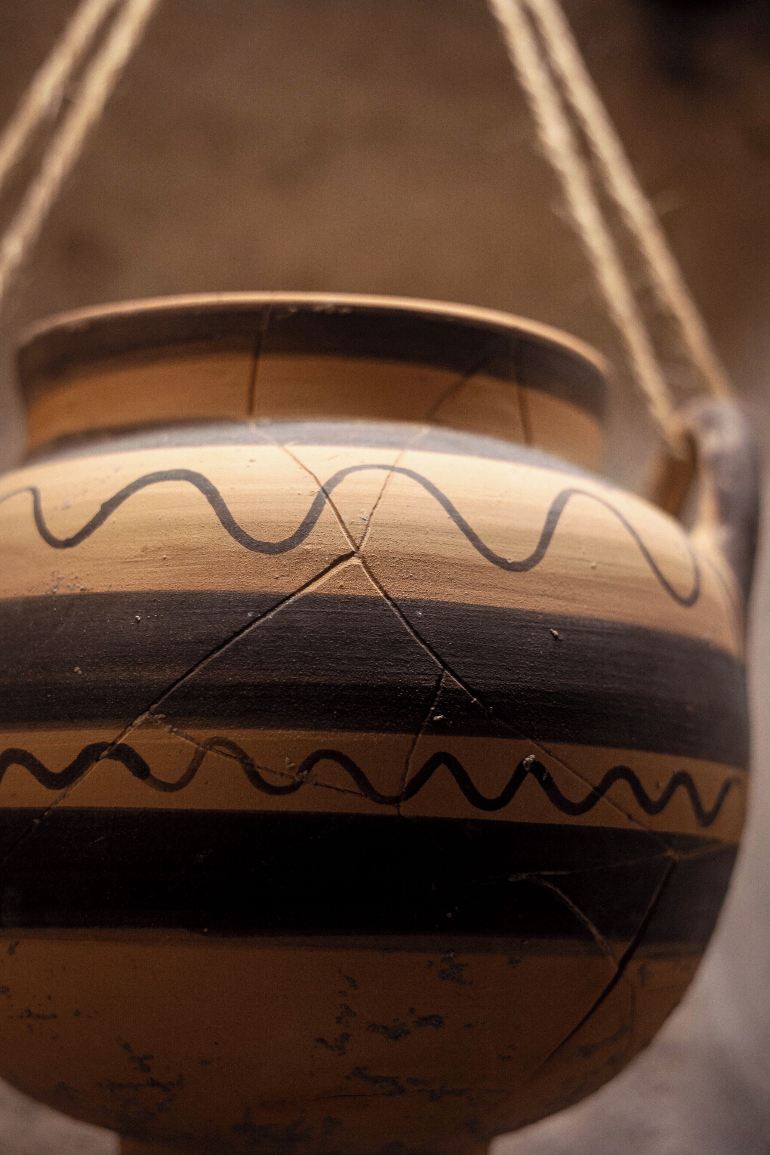 A ceramic pot with a wavy pattern and visible cracks.