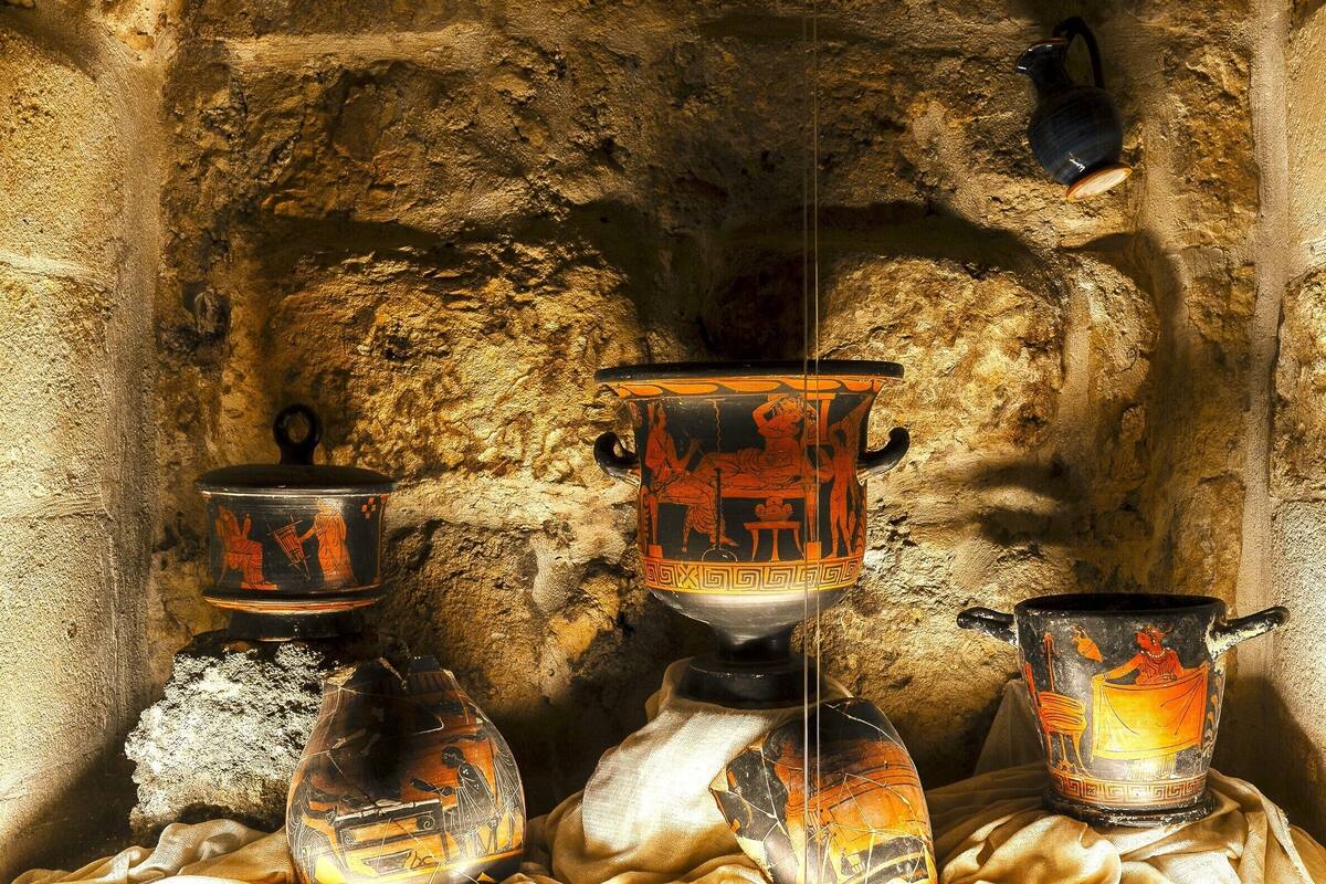 A stone wall with a metal rack holding pottery.