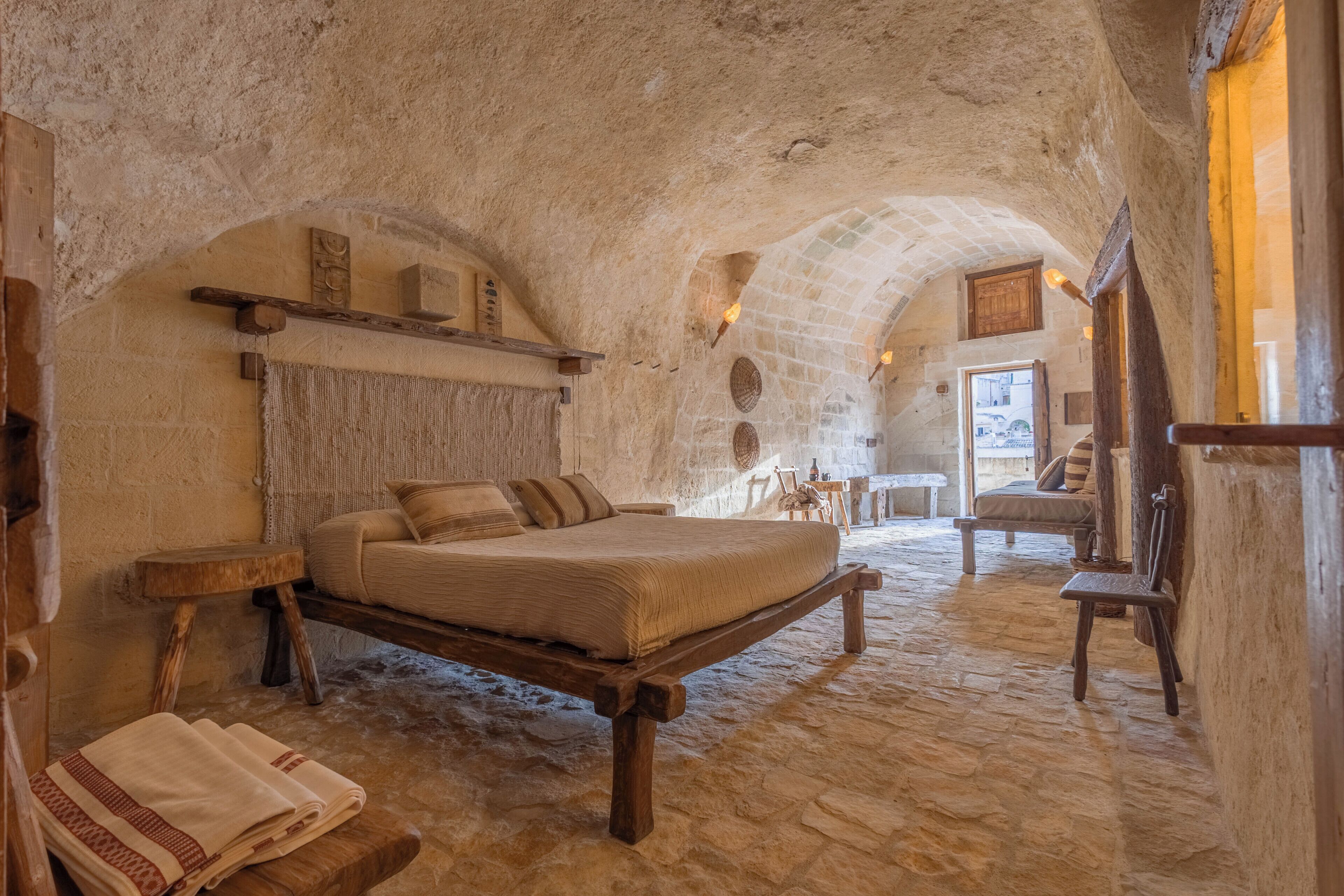 Una habitación rústica con una cama, muebles de madera y paredes de piedra.