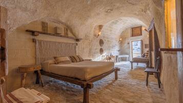 Una habitación rústica con una cama, muebles de madera y paredes de piedra.
