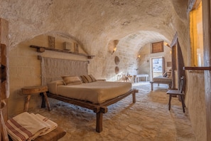 A rustic room with a bed, wooden furniture, and stone walls. - Moyseion Matera - Adults Only (Matera)