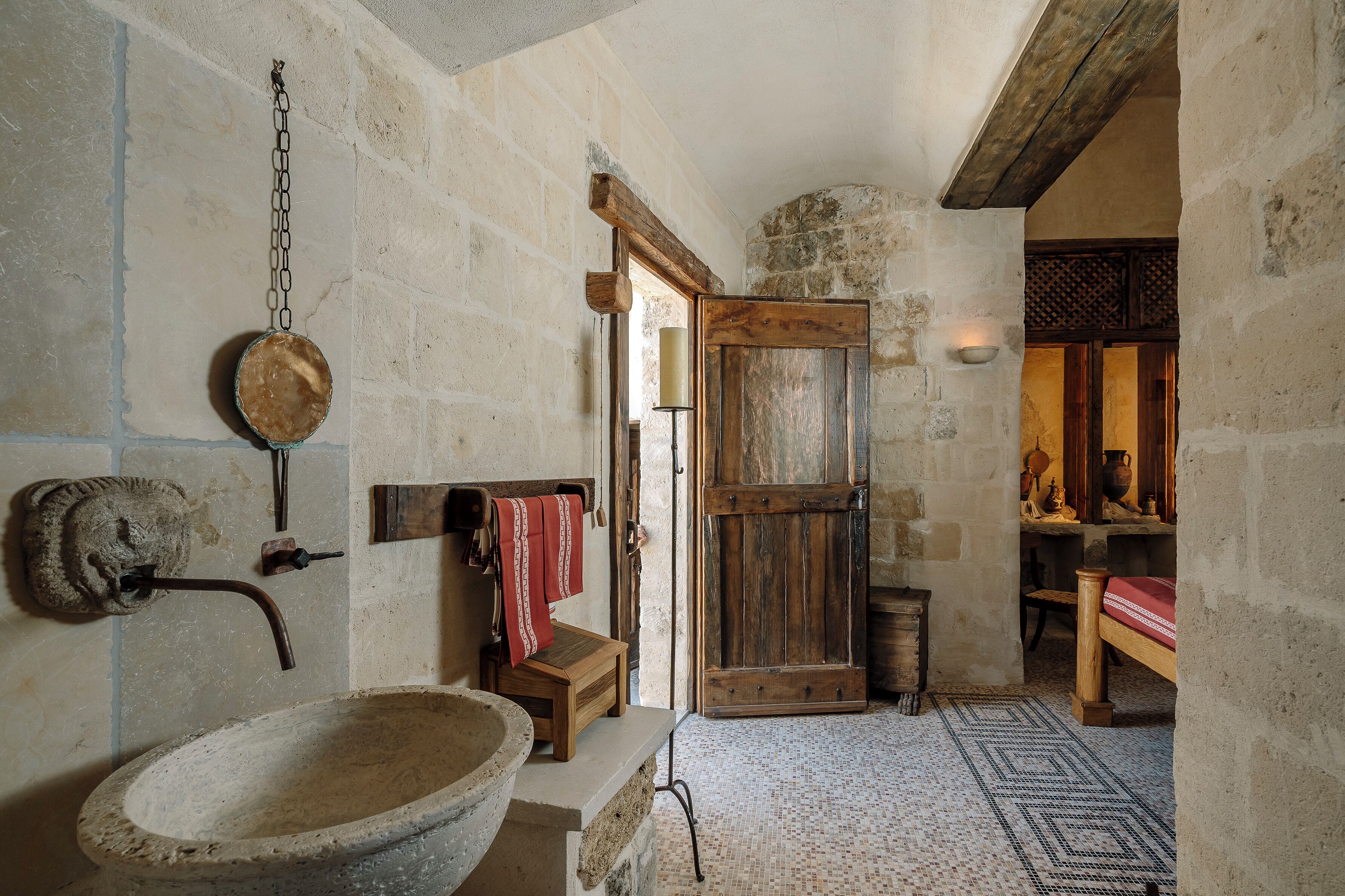 Un baño rústico con un lavabo de piedra, puerta de madera y suelo de baldosas.