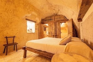 A rustic bedroom with a wooden bed, a bench, and a small window. - Moyseion Matera - Adults Only (Matera)