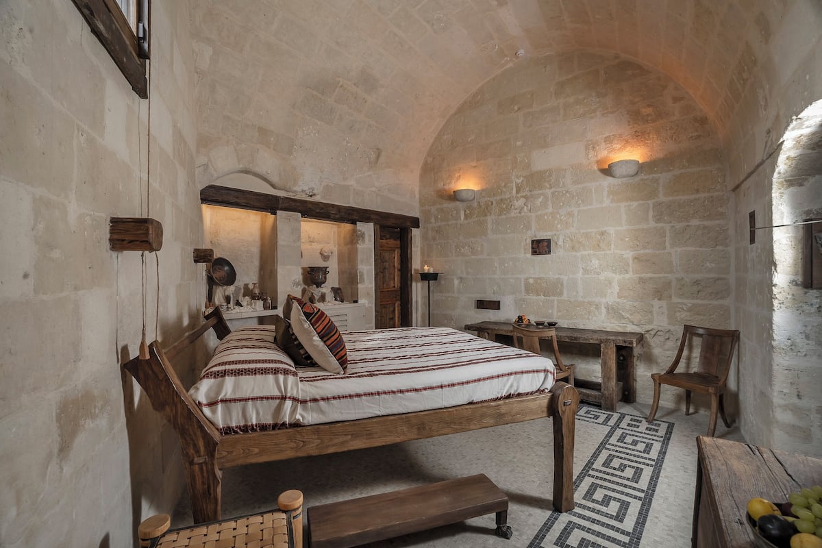 A rustic bedroom with a wooden bed, a small table, and a bench.